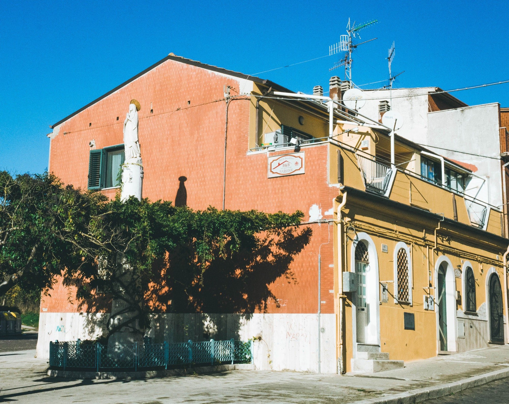 L'edificio con la statua della Madonna e la veduta della strada