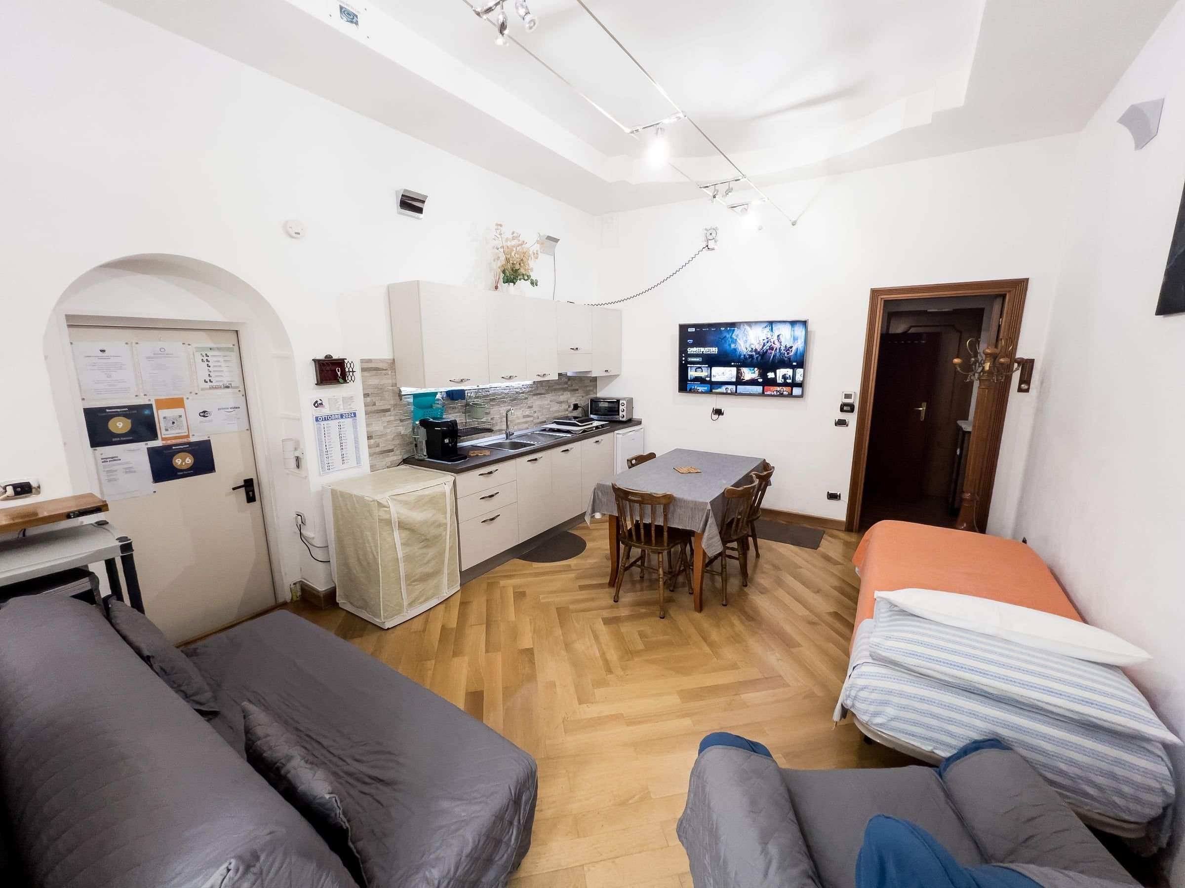 La zona giorno vista d'insieme: divani, tavolo, angolo cottura e letto singolo